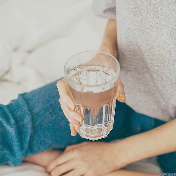 Seminare für Frauen: Junge Frau hält ein Glas mit Wasser in der Hand