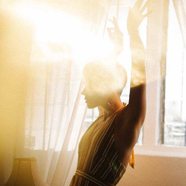 Energievampire: Frau steht vor einem Fenster mit der Sonne im Rücken